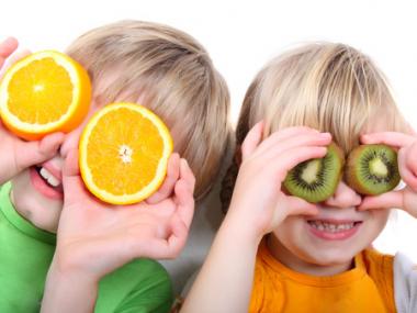 Glade børn der bruger frugter som kikkert for øjenene